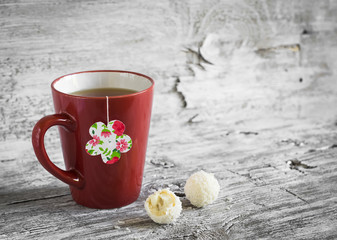 tea in a red cup and a homemade tea bag on a light wooden background, vintage style