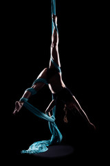 Young woman gymnast with blue gymnastic aerial silks