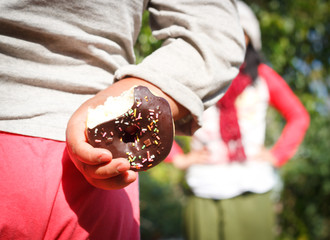 little boy hiding a chocolate donuts behind his back