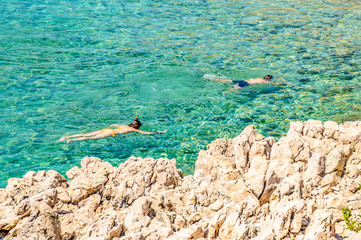 A couple snorkeling in the crystal clear rocky Adriatic sea