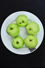 Guava on white dish on black background