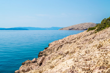 Rocky coastline with crystal clear blue Adriatic sea with island