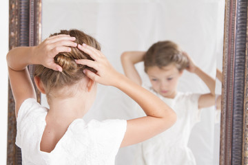 Child fixing her hair while looking in the mirror.