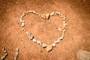 A heart made of stones on the red earth ground with an artistic