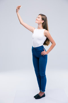 Happy female teenager making selfie photo on smartphone