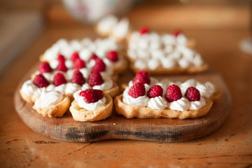Cream eclairs with fresh raspberries on wood table, cooking