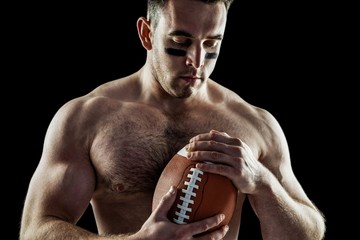 Shirtless American football player with ball