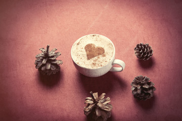 Obraz na płótnie Canvas Cup of coffee with heart shape and pine cones