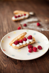 Cream eclairs with fresh raspberries, stilllife