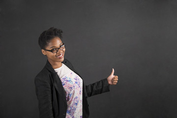 African woman with thumbs up hand signal on blackboard background