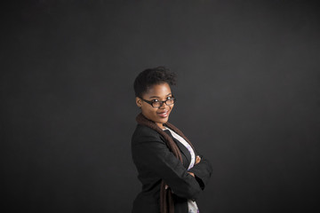 South African or African American woman teacher or student with arms folded on chalk black board background