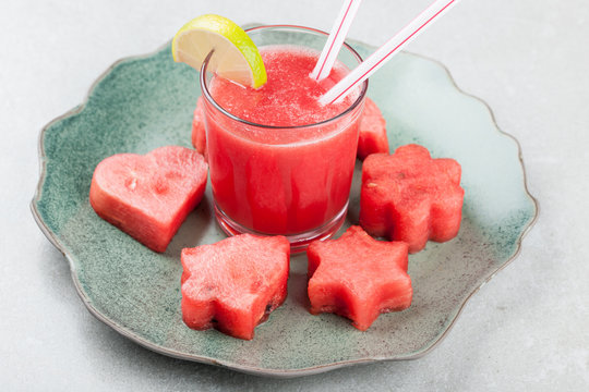 Glass of watermelon juice with ice and watermelon figurines