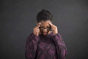 African woman with fingers on temples thinking on blackboard background