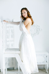 Cute young woman wearing white dress sitting on the chair