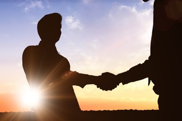 Composite image of silhouettes shaking hands