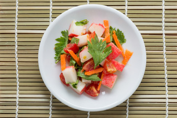 Crab stick spicy salad with vegetable on wood background