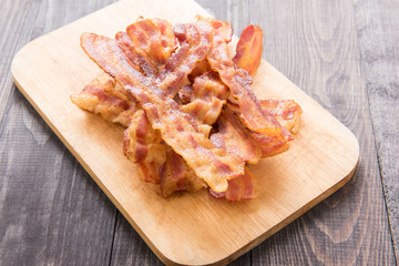 Fried bacon strips on the wooden board