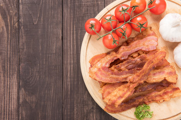 Fried bacon, tomato and garlic on the wooden board