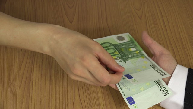 Woman hand take 100 euro cash banknote bribe from envelope and give it to man in suit. Corruption concept. Illegal payment for works. Shadow economy. Closeup shot. 4K UHD video clip.

