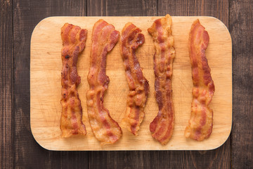 Fried bacon strips on the wooden board