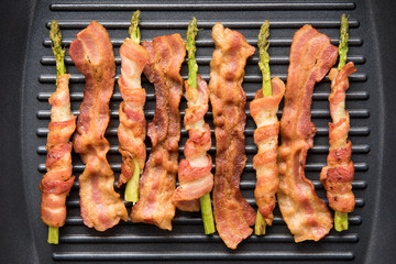 Bacon slice and asparagus wrapped in bacon being cooked in fryin