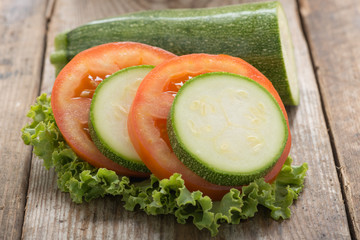 Tomato and  zuchini slice on wood background, close-up