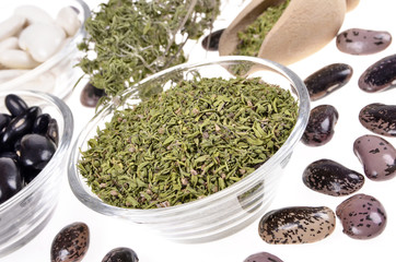 dried winter savory, lima beans in a glass bowl  on a white background,selective focus..