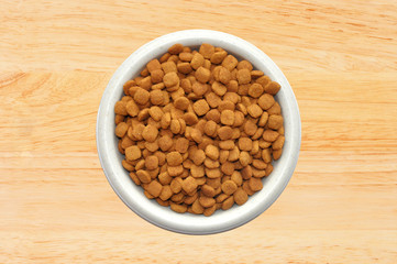 Dry cat food in plate over wooden background