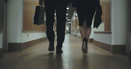 Rear view of two business people walking down office corridor 