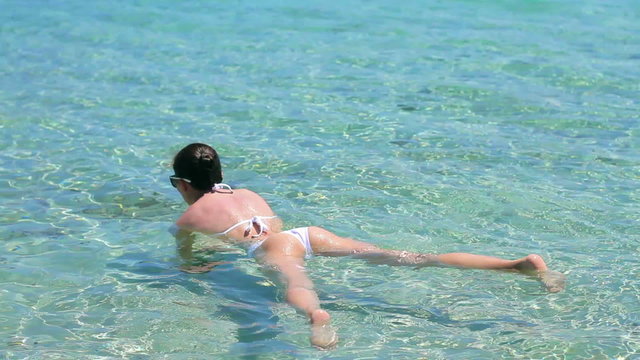 Tourist woman on summer holidays floating on a turquoise water, rear view