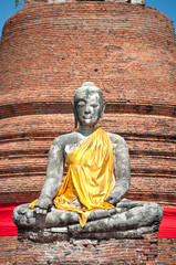 Fototapeta premium Broken Buddha with yellow sash at Wat Worachet Tharam, Ayutthaya, Thailand
