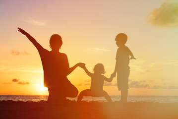 Fototapeta na wymiar father with kids silhouettes having fun at sunset