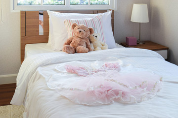 white bedroom decorative with girl dress, pillows and dolls on b