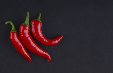 Three peppers on a black background. Three chilli peppers.