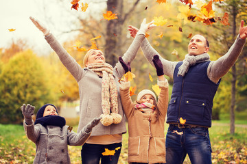 happy family playing with autumn leaves in park