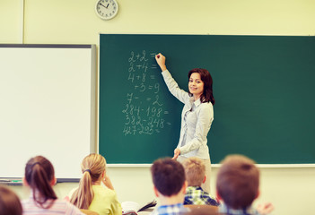 school kids and teacher writing on chalkboard