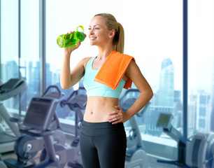 happy woman drinking water from bottle in gym