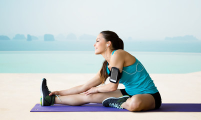 smiling woman stretching leg on mat over pool