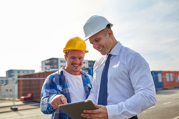 happy builders in hardhats with tablet pc outdoors