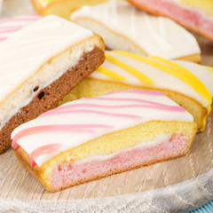 Cake Slices - Variety of colourful cake slices on a wooden board.
