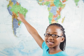 Smiling pupil pointing on world map in a classroom