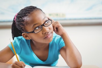 Cute african american pupil daydreaming at her desk in a classroom - Powered by Adobe