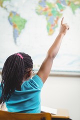 Obraz na płótnie Canvas Rear view of pupil raising hand in a classroom