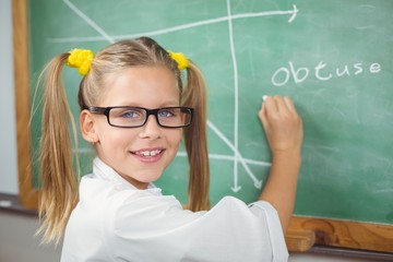 Cute pupil with lab coat writing on chalkboard