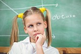 Cute pupil with lab coat thinking in front of chalkboard
