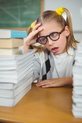 Overwhelmed pupil between stack of books on her desk