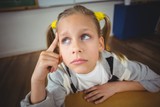 Thoughtful pupil sitting at her desk in a classroom
