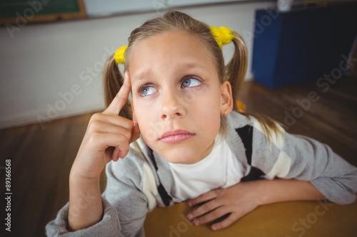 Thoughtful pupil sitting at her desk in a classroom
