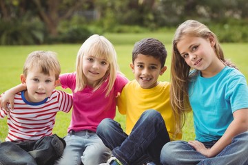 Fototapeta premium Smiling classmates sitting in grass 