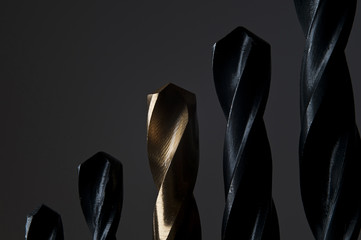 photo of golden and black drill bits placed on dark background. Macro studio shot